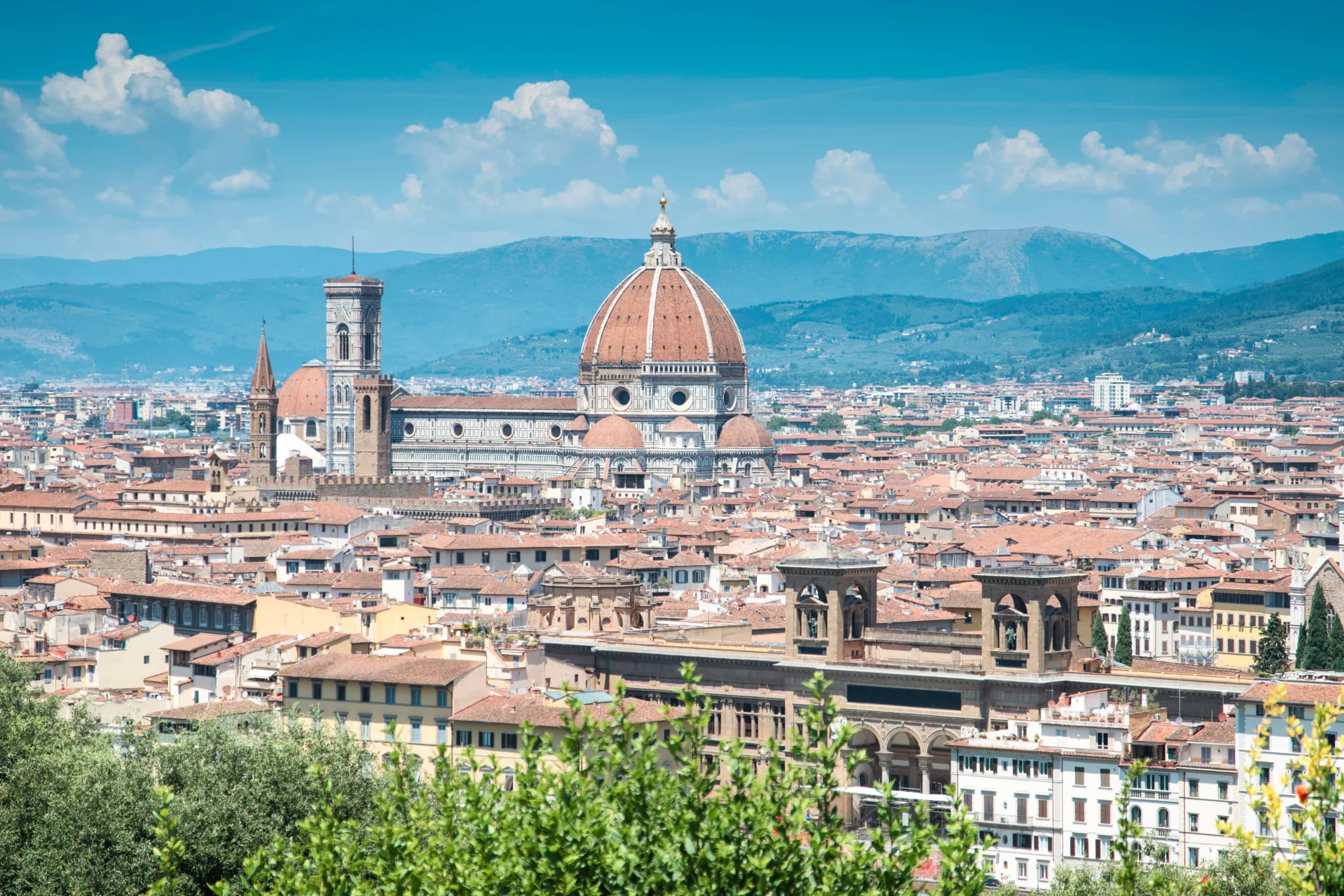 A stunning view of Florence featuring the iconic Santa Maria del Fiore under a bright blue sky.